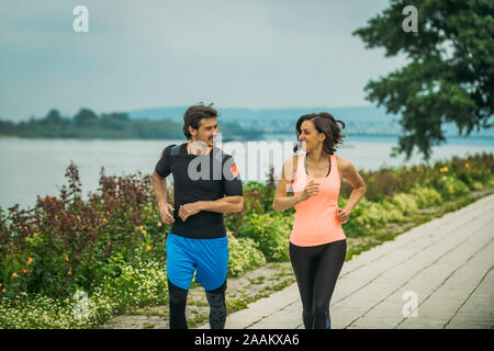 Die Ausübung durch den Fluss mit Personal Trainer. Stockfoto