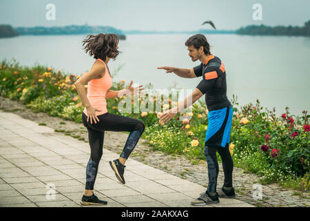 Die Ausübung durch den Fluss mit Personal Trainer. Stockfoto