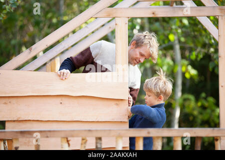 Vater und Sohn bauen Baumhaus im Garten Stockfoto