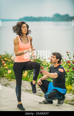 Die Ausübung durch den Fluss mit Personal Trainer. Stockfoto