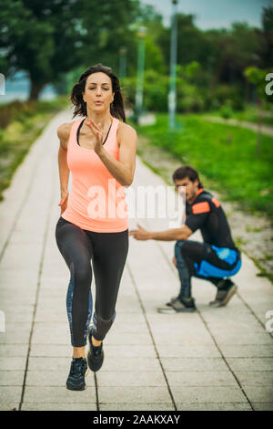Die Ausübung durch den Fluss mit Personal Trainer. Stockfoto