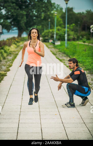 Die Ausübung durch den Fluss mit Personal Trainer. Stockfoto
