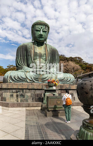 Kamakura, Japan - November 1., 2018: ein Besucher betet vor der riesigen Buddha Statue am Kotokuin Tempel in Kamakura, Japan Stockfoto