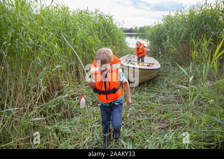 Brüder spielen auf dem Boot im Gras Feld günstig Stockfoto