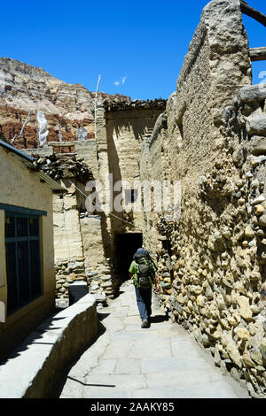 Trekker wandern in eine enge Gasse, Chuksang, Upper Mustang, Nepal. Stockfoto