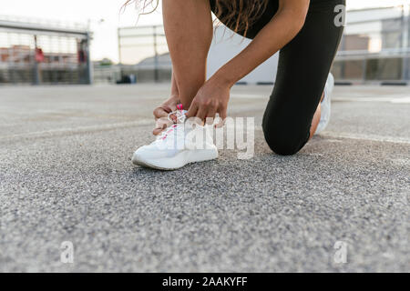 Junge Frau Schnürsenkel binden auf der Dachterrasse Stockfoto