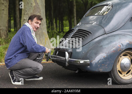 Mann zur Festsetzung vintage Auto auf Landstraße Stockfoto