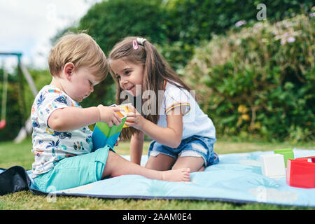 Schwestern spielen mit Blocks auf der Picknickdecke Stockfoto