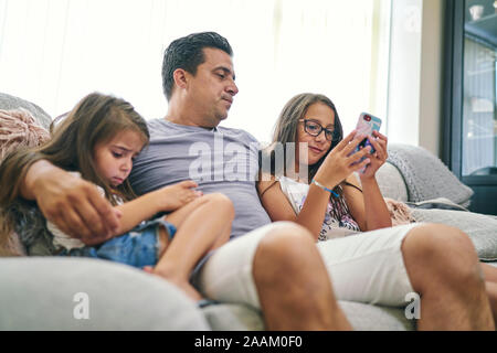 Vater, Töchter spielen Computer Spiele auf Handy Stockfoto