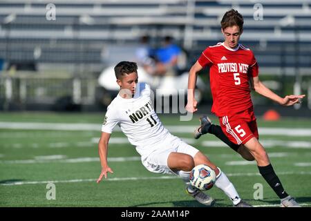 Spieler, der auf den Rasen fällt, während er versucht, den Ball vor ihm zu kontrollieren, während er von einem Gegner genau kontrolliert wird. USA. Stockfoto