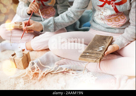 Zwei Mädchen malen auf Holz. Der Weihnachtszeit. Selektive konzentrieren. Stockfoto