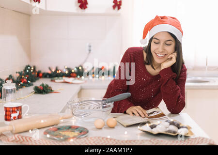 Lächelnde Frau lesen Buch über Küche Bar mit Süßigkeiten Stockfoto