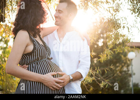 Mann lächelnd und berühren Bauch der schwangeren Frau im Park Stockfoto