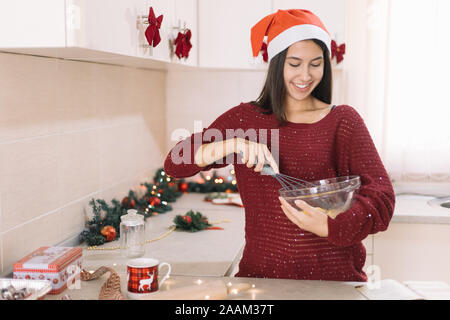 Mädchen, dass Schüssel und Schlagsahne Eier mit Rührwerk Stockfoto