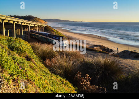 Coaster Passagier Diesellok Reisen entlang der Küste Eisenbahnschienen unter Brücke bei Sonnenuntergang, in der Nähe von Torrey Pines Park, La Jolla, Kalifornien, USA Stockfoto