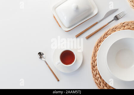 Weißer keramik geschirr, Fibre geflochtene runde Tischset und Besteck auf weißem Hintergrund. Im skandinavischen Stil Stockfoto
