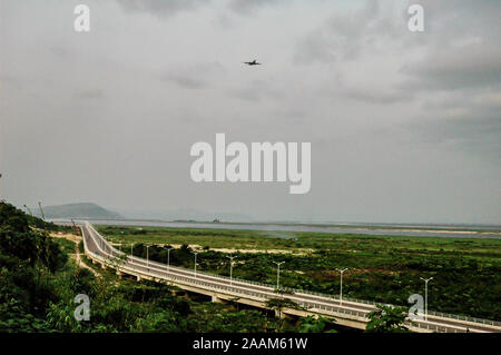 Flugzeug in bewölkten Himmel über der Autobahn, Route de la Corniche von Makélékélé zu Bacongo in der Nähe von Brazzaville in der Republik Kongo. Stockfoto