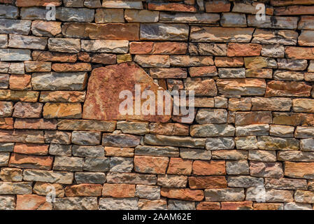 Allgemeiner Hintergrund eines nicht an der Wand der irregulären grungy nicht spitzen Steinen im Sommer Farben in der Sonne mit ihren Schatten auf die Steine Stockfoto