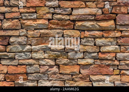 Allgemeiner Hintergrund eines nicht an der Wand der irregulären grungy nicht spitzen Steinen im Sommer Farben in der Sonne mit ihren Schatten auf die Steine Stockfoto