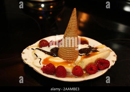 Eis drehte sich auf Eis, Karamell, Schokolade und Himbeeren Stockfoto