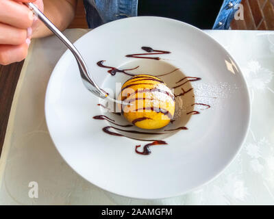 Geschmackvoll eingerichteten gebratenes Eis Dessert auf einem weißen Teller mit der Gabel in der Hand. Flach, Ansicht von oben. Typisch chinesisches Gebäck. Stockfoto