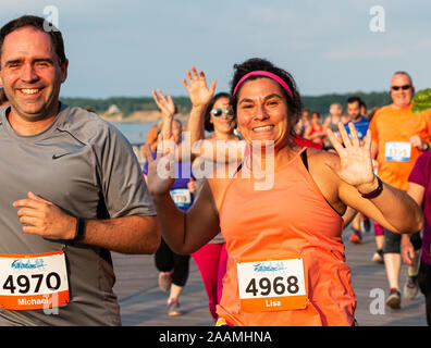 Kings Park, New York, USA - 17. Juni 2019: Läufer auf dem Boardwalk lächeln und winken in die Kamera während des Sommers Serie 10 K An Wanne Wiese Stat Stockfoto