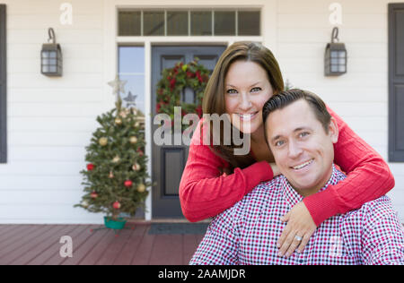 Glückliches junges Paar auf der Veranda des Hauses mit Weihnachtsschmuck. Stockfoto