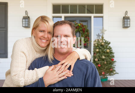 Glückliches junges Paar auf der Veranda des Hauses mit Weihnachtsschmuck. Stockfoto