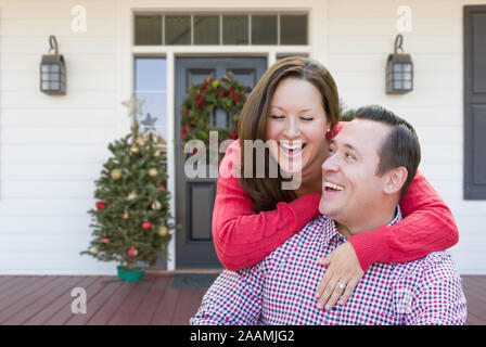 Glückliches Junges Paar lachend auf der Veranda des Hauses mit Weihnachtsschmuck. Stockfoto