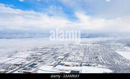 Eine Antenne/drone Blick über eine kleine Stadt in Illinois auf der Suche nach einem Schneesturm mit den Wolken starten zu löschen und die Stadt bedeckt. Stockfoto