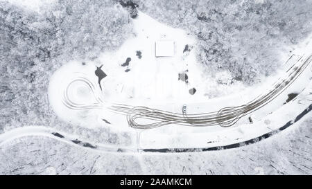 Eine Drohne/Luftaufnahme der Weg bedeckt mit Schnee und Eis. Linien haben, die von den Autos durchfahren geschnitzt. Stockfoto