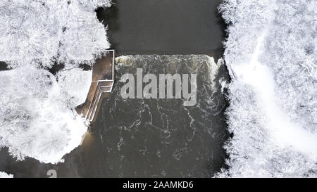 Eine Drohne / Luftaufnahme eines kleinen Wasserfalls und mit Blick auf Plattform mit schneebedeckten Bäumen umgeben. Stockfoto