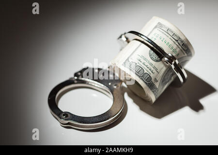 Handschellen Gesperrt auf Rolle von einem Hundert-euro-Scheine unter Spotlight. Stockfoto