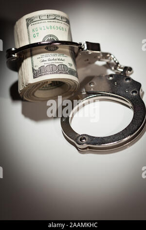 Handschellen Gesperrt auf Rolle von einem Hundert-euro-Scheine unter Spotlight. Stockfoto