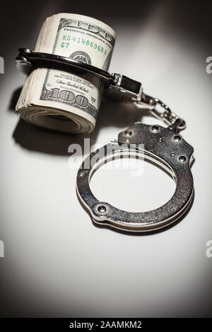 Handschellen Gesperrt auf Rolle von einem Hundert-euro-Scheine unter Spotlight. Stockfoto