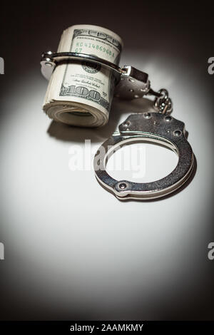 Handschellen Gesperrt auf Rolle von einem Hundert-euro-Scheine unter Spotlight. Stockfoto