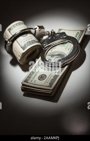 Handschellen Gesperrt auf Rolle von einem Hundert-euro-Scheine unter Spotlight. Stockfoto
