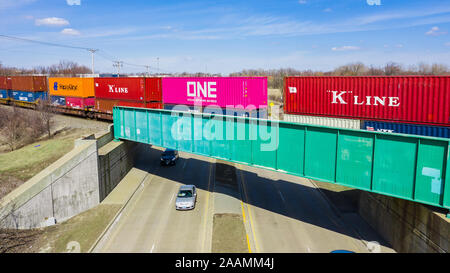 Eine Drohne/Luftaufnahme eines Zuges schleppen Container über eine Straße gehen. Stockfoto