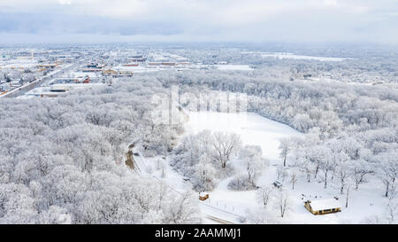 Eine Antenne/drone Blick über eine kleine Stadt in Illinois auf der Suche nach einem Schneesturm mit den Wolken starten zu löschen und die Stadt bedeckt. Stockfoto