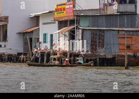 Cai, Mekong Delta, Vietnam - März 13, 2019: Entlang der Kinh 28 Kanal. Familie kehrt in kleinen Cano aus schwebenden Großhandelsmarkt vorbei Business b Stockfoto