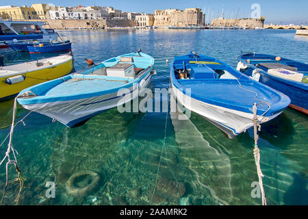 Typische Süditalien Fischerboote bei Gallipoli Hafen sitzen Vor der mittelalterlichen Burg an einem sonnigen und warmen Herbst Tag Stockfoto