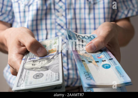 Hand, cash Banknote von 1000 Philippinen Peso und US-Dollar. Geldwechsel Stockfoto