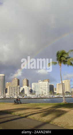 Honolulu, Hawaii, USA - 10. Juni 2015: Blick auf Honolulu's Skyline mit einem wunderschönen Regenbogen über den Himmel von der Magic Island Lagune Stockfoto