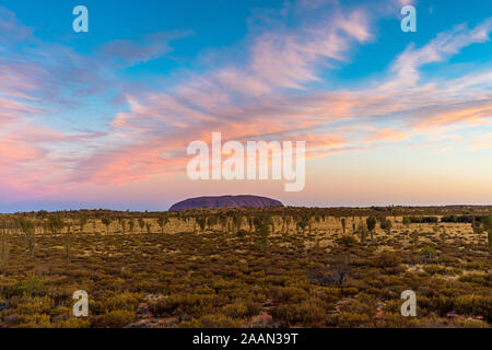 Uluru, auch Ayers Rock genannt, bei Sonnenuntergang mit interessante Wolkenformationen über. Northern Territory, Australien. Stockfoto