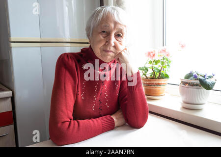 Ältere einsame Frau gedrückt Sitzen am Tisch Stockfoto