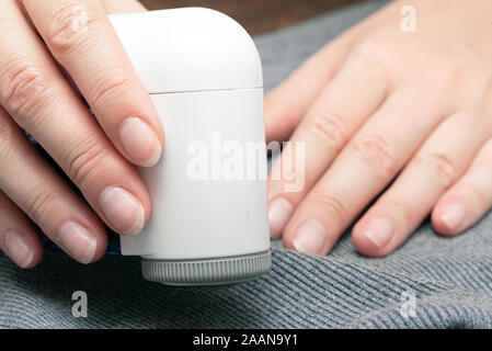 Frau Reinigt Kleider aus einem Schieber mit einem Pellet remover hautnah. Stockfoto