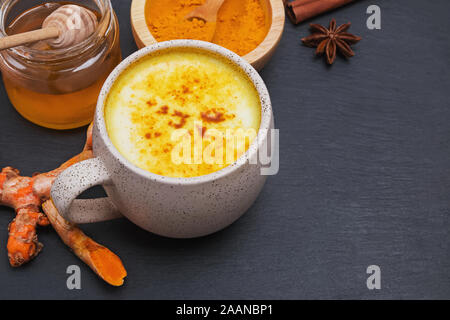 Gewürzten orientalischen Getränk mit kurkuma Pulver und Honig in einer Tasse auf schwarz Tabelle schließen Stockfoto