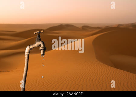 Wasserhahn, tropft und Wüste im Hintergrund, Konzept der Austrocknung des Planeten und Wasserknappheit Stockfoto