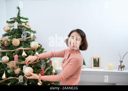 Schöne junge Frau schmücken Weihnachtsbaum schmücken Weihnachtsbaum Stockfoto