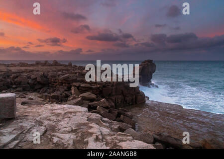 Portland Bill Dorset England rosa gefärbten Wolken hinter Pulpit Rock, wie der Sonnenaufgang beginnt zu verblassen. Stockfoto